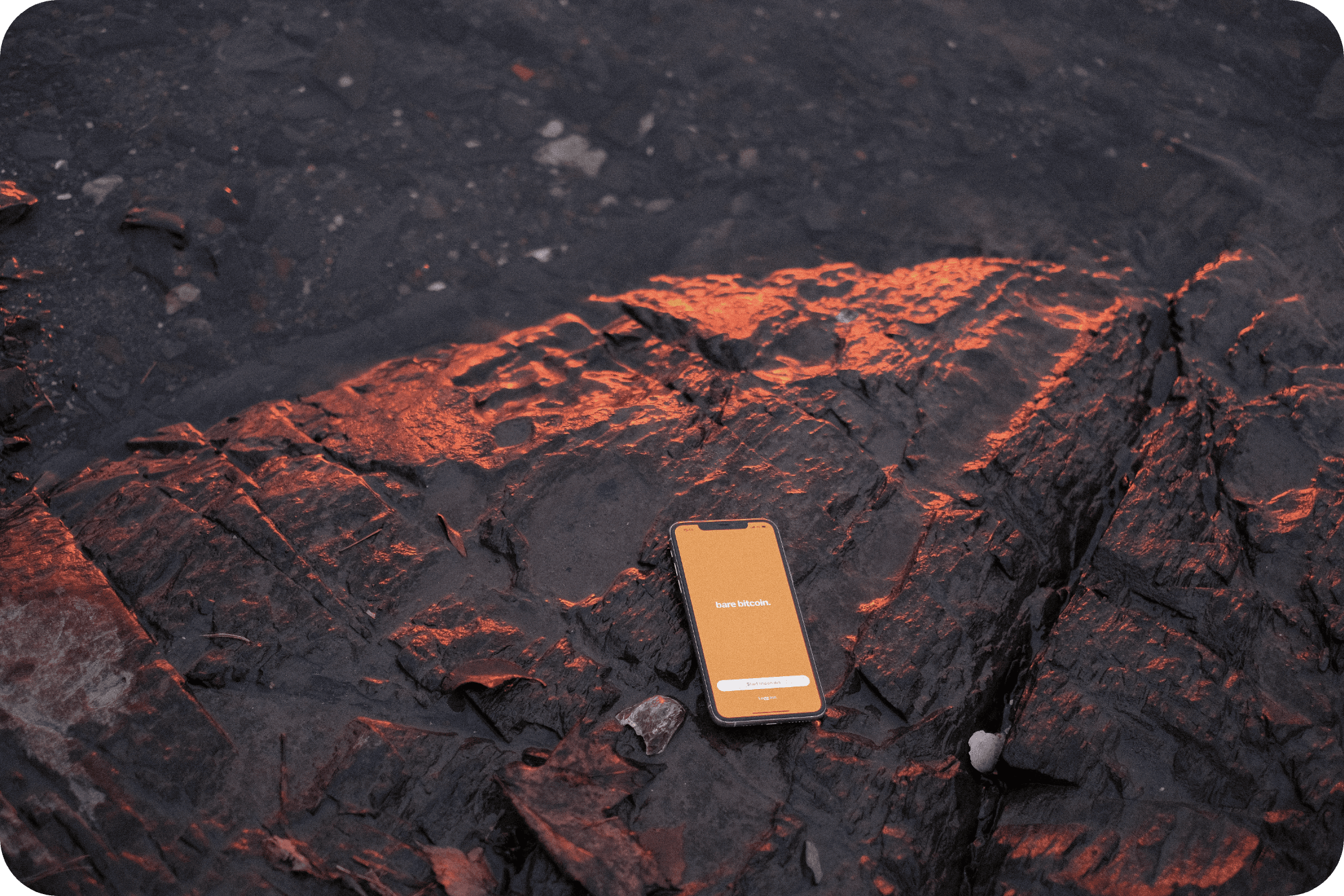En mobil som ligger på en stein, med Bare Bitcoin-appen åpnet